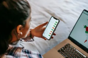 Investitor verificând pe telefon cât scade bursa și analizând portofoliul în timpul unei corecții